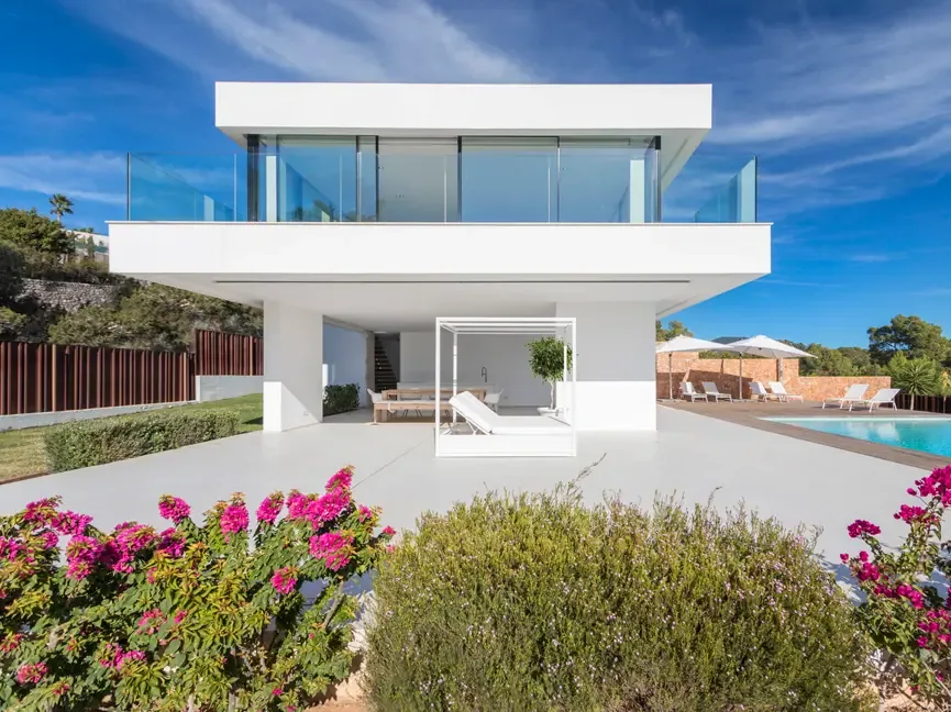 Villa Vista Alegre con volúmenes blancos, piscina desbordante, buganvilla en flor y pinar al fondo bajo cielo azul.