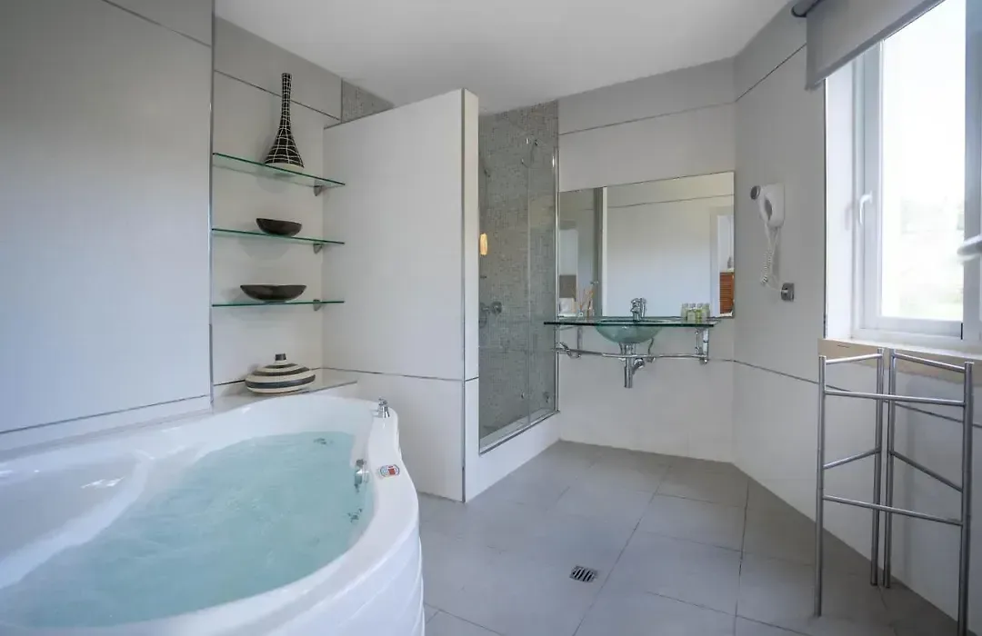 Baño con bañera de hidromasaje en esquina, estantería de obra y luz natural desde el patio.
