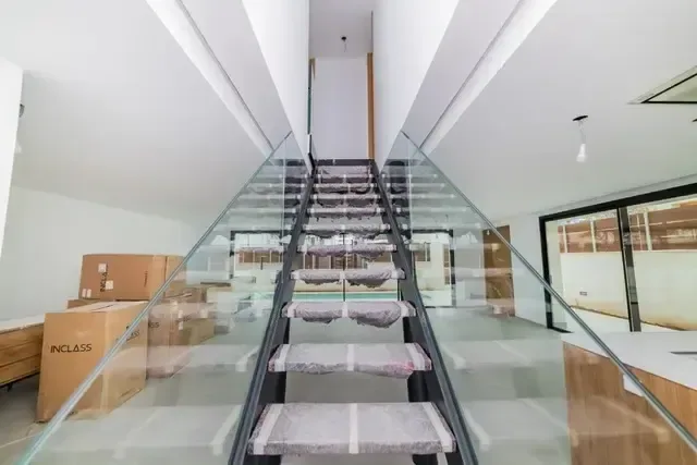 Escalera de peldaños de vidrio con estructura de acero, vista en picado desde la planta superior.