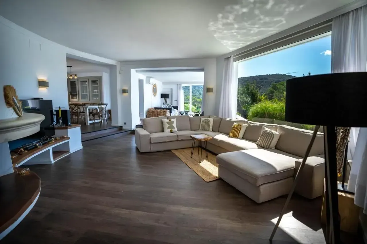 Salón con suelo de madera oscura, sofás en tonos crudos y ventanal corrido hacia la terraza.