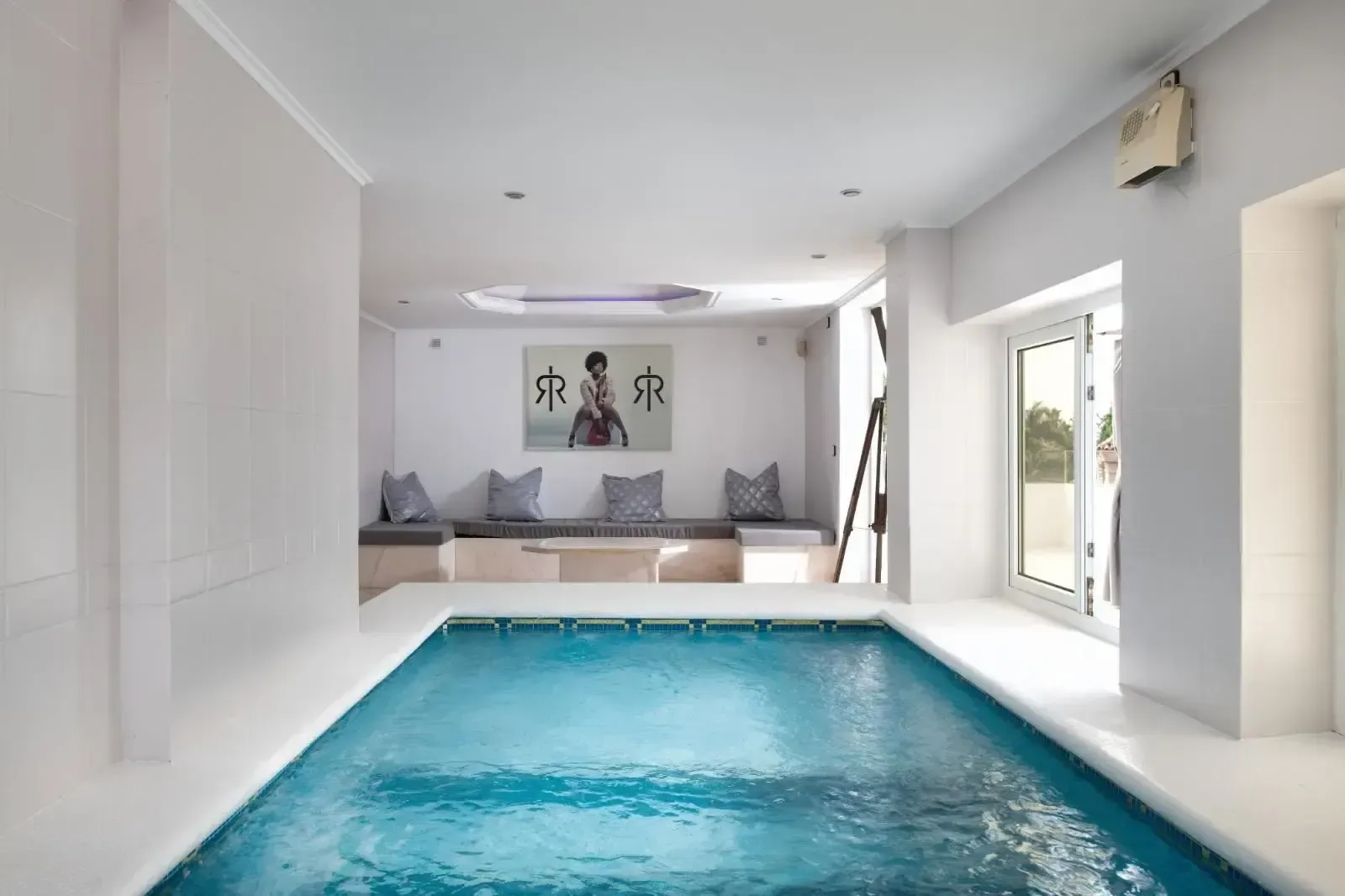 Piscina interior climatizada, con acabados claros continuos entre el vaso y el pavimento.
