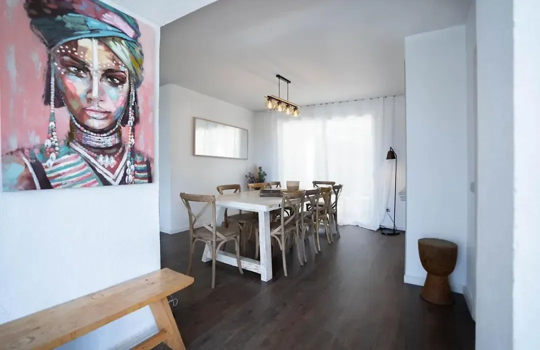 Rincón de comedor con mesa blanca y un retrato de gran formato como única pieza de color.