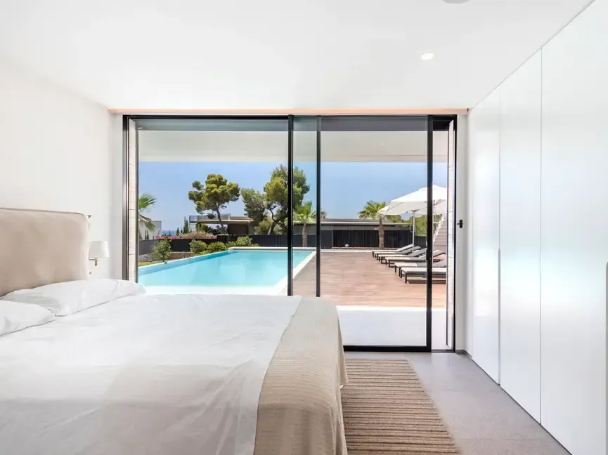 Dormitorio con carpintería de suelo a techo y salida directa a la terraza junto a la piscina.
