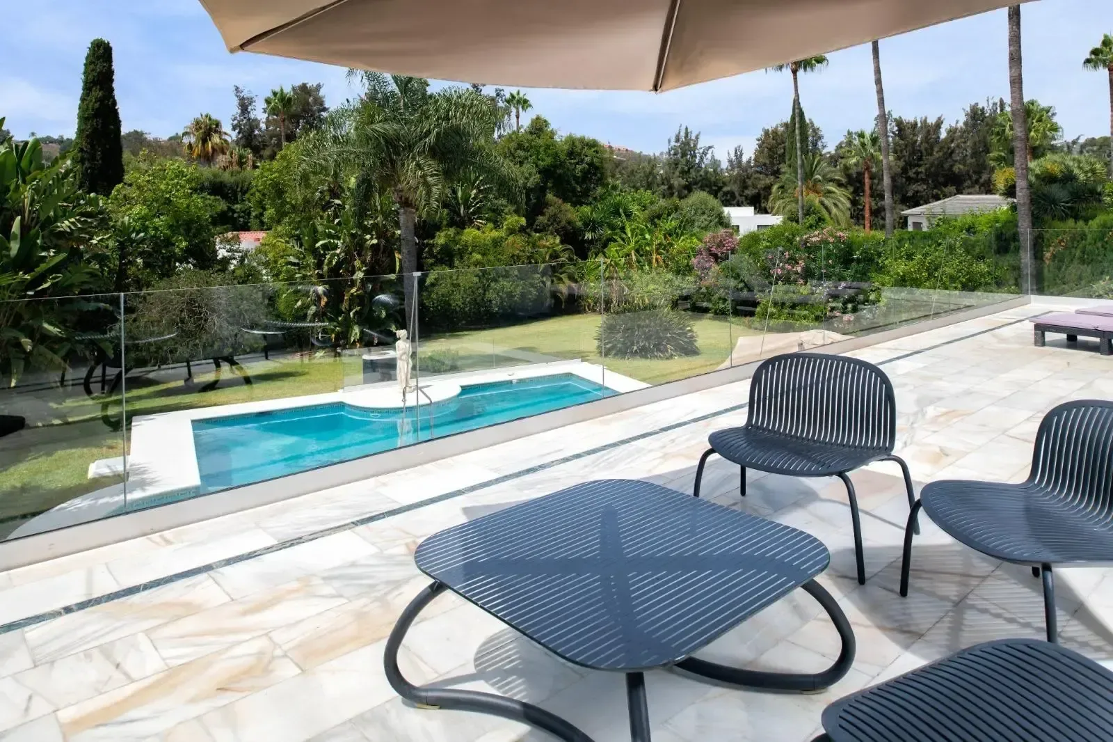 Terraza cubierta junto a la piscina, con mobiliario de exterior y sombra construida.