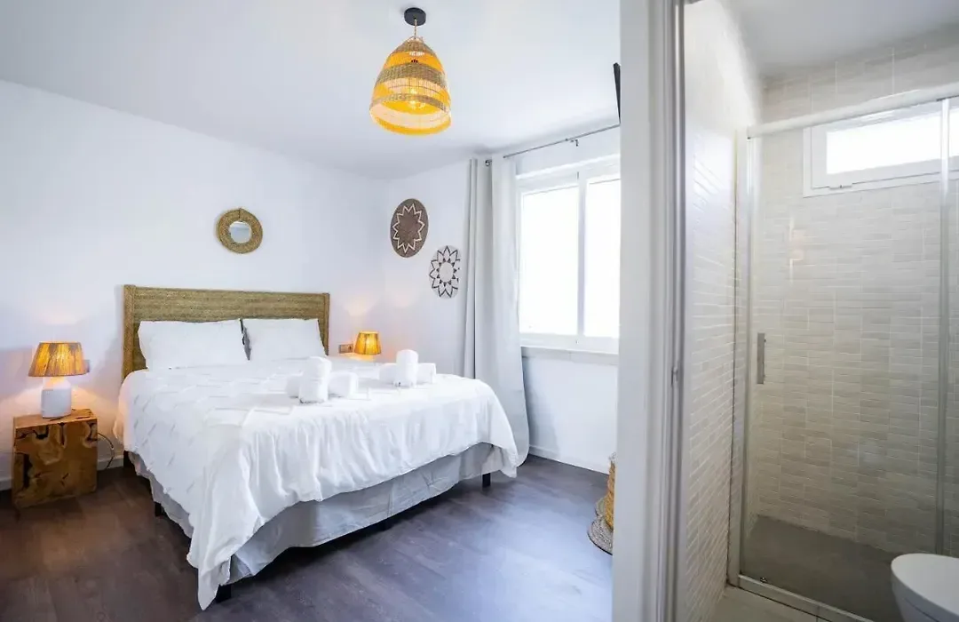 Dormitorio con lámpara de mimbre y paso al baño propio.