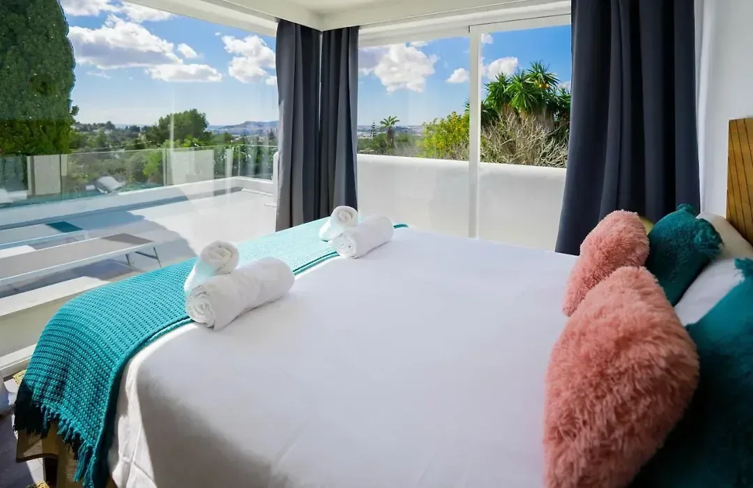 Dormitorio con textiles en turquesa y rosa y salida directa a la terraza superior.