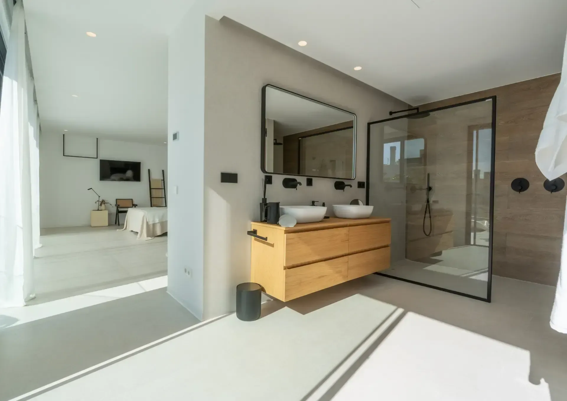 Vestidor pasante que conecta el dormitorio con el baño, con mueble de doble seno y espejo de gran formato.