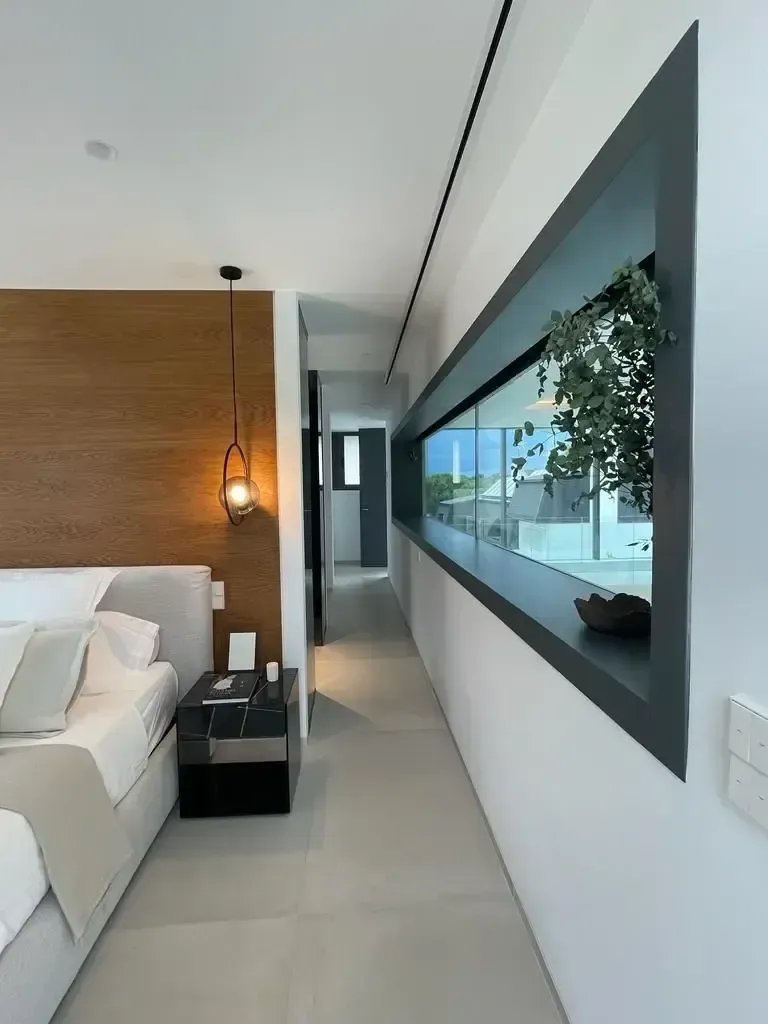 Sala de estar con televisor integrado en el paramento y gran hueco horizontal hacia la vegetación.